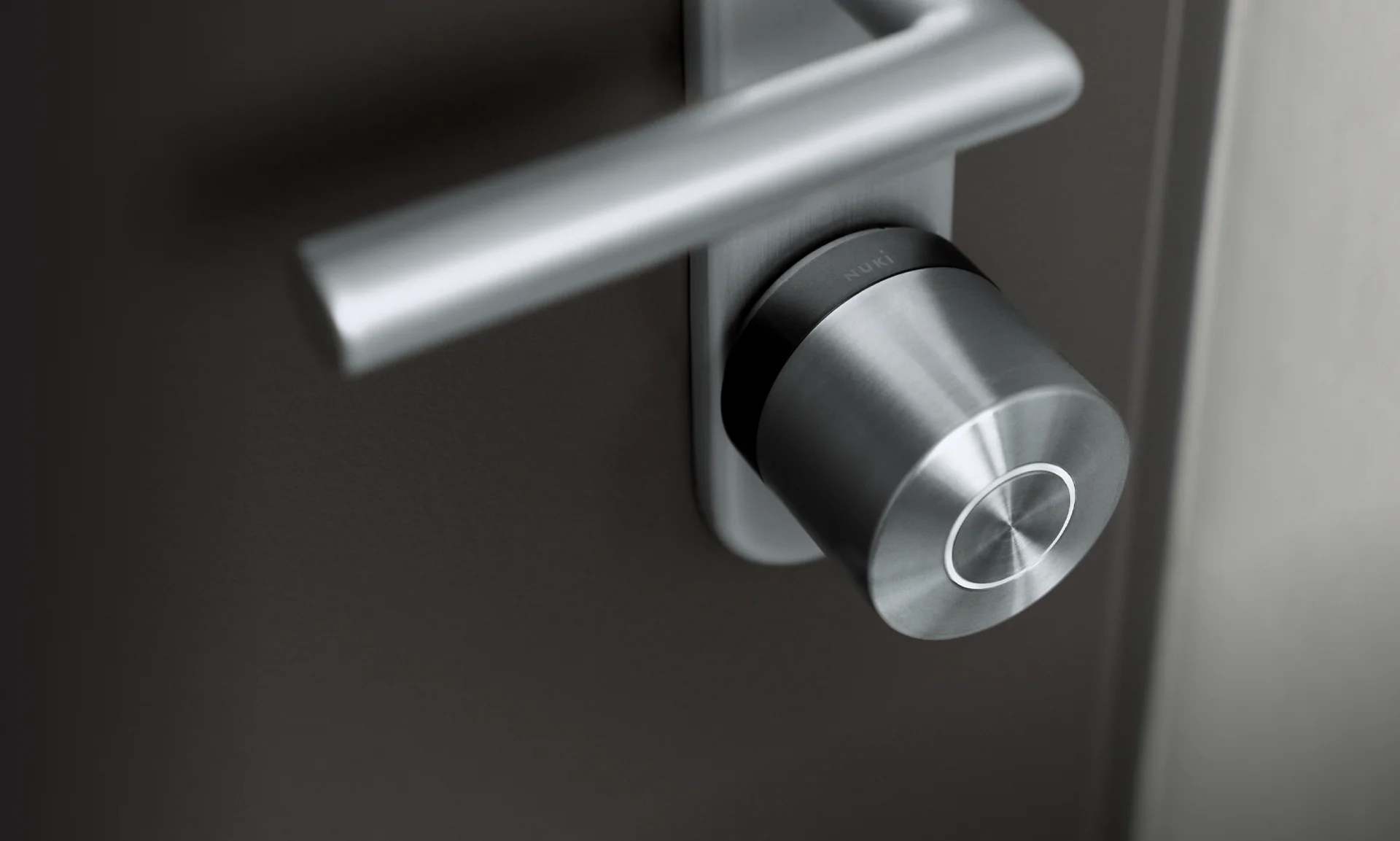 Primo piano di Nuki Smart Lock Ultra argento montata su porta scura.