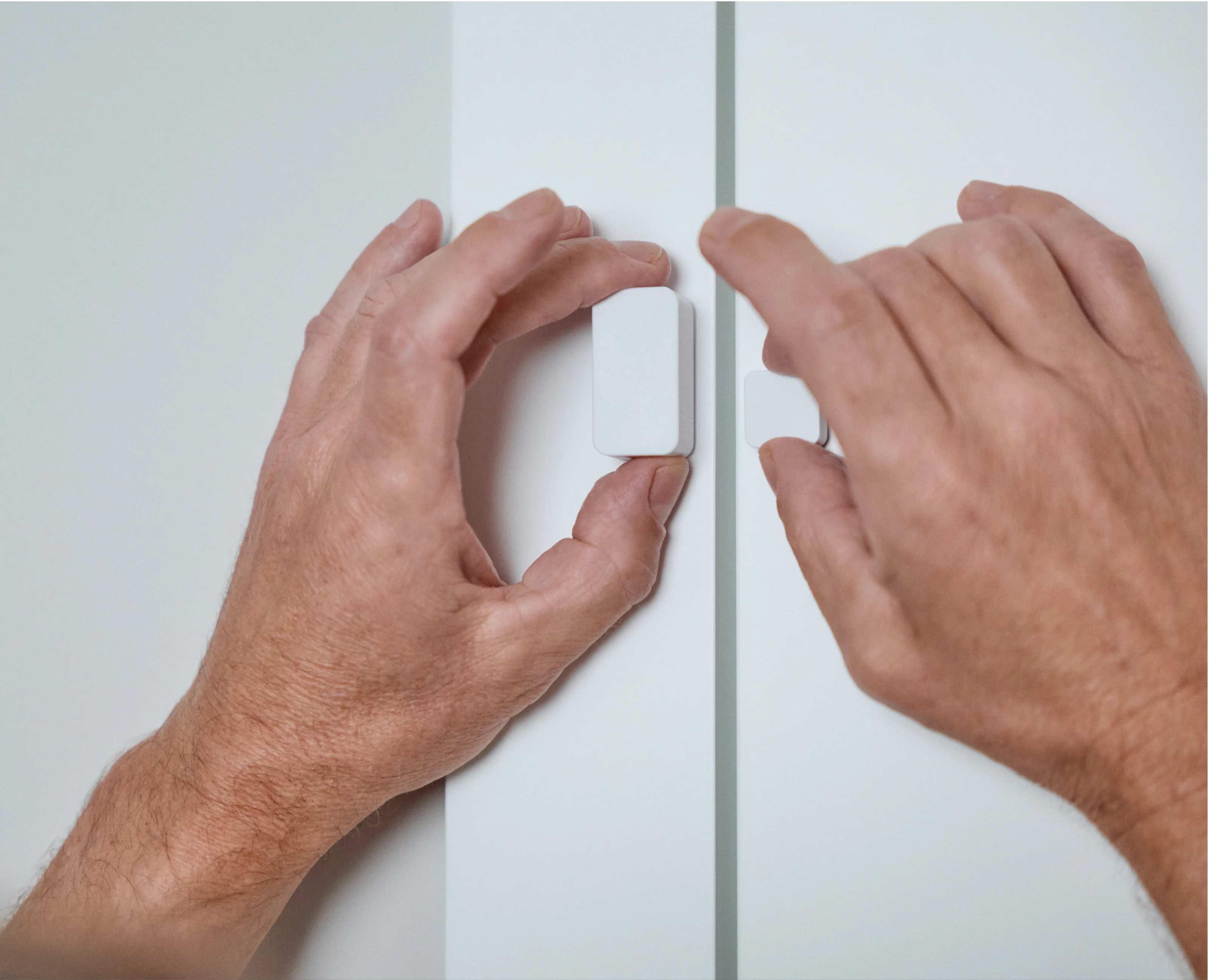Mani che installano il Nuki Door Sensor sul telaio della porta.