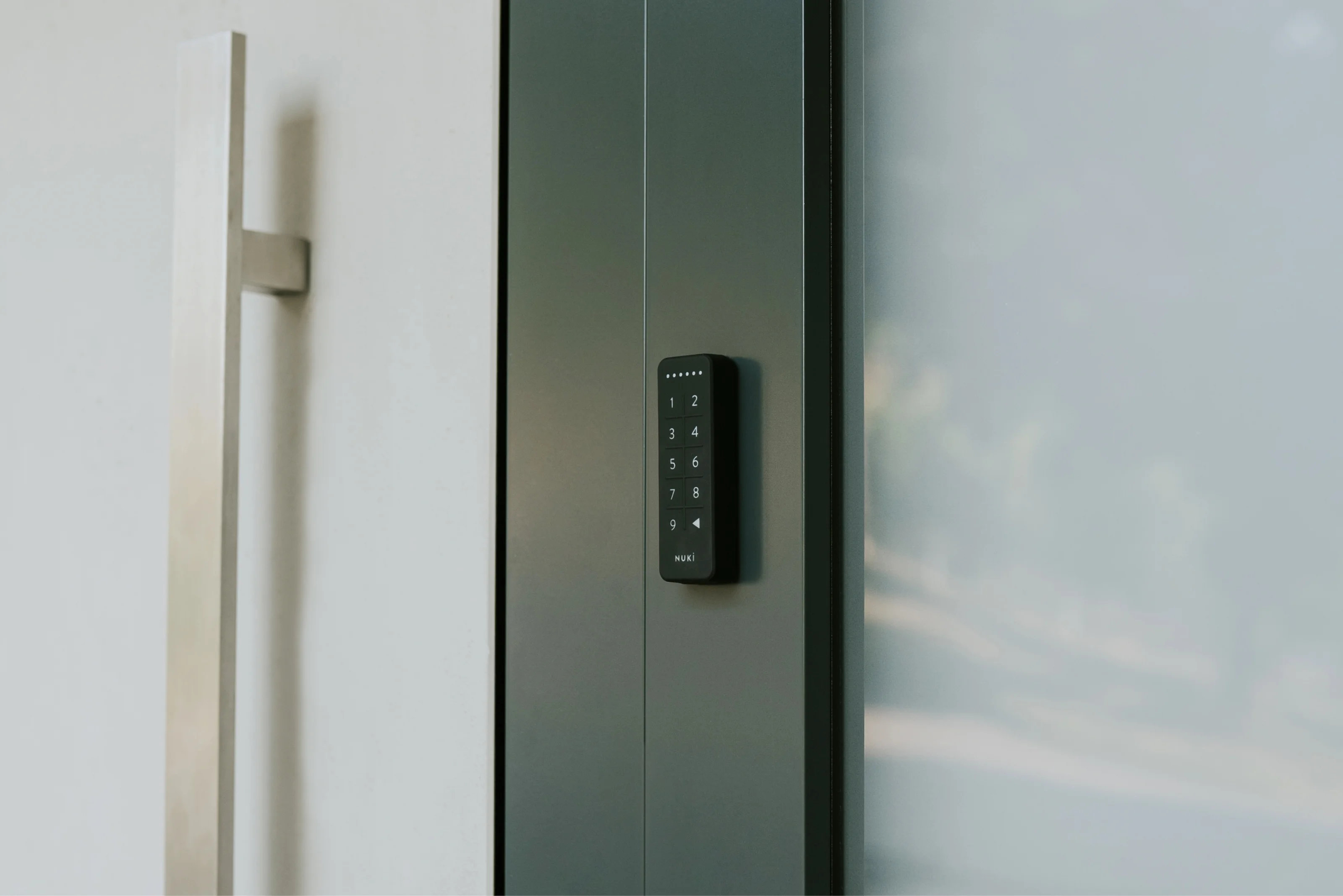Nuki Keypad montato accanto a una porta d’ingresso moderna per accesso senza chiavi