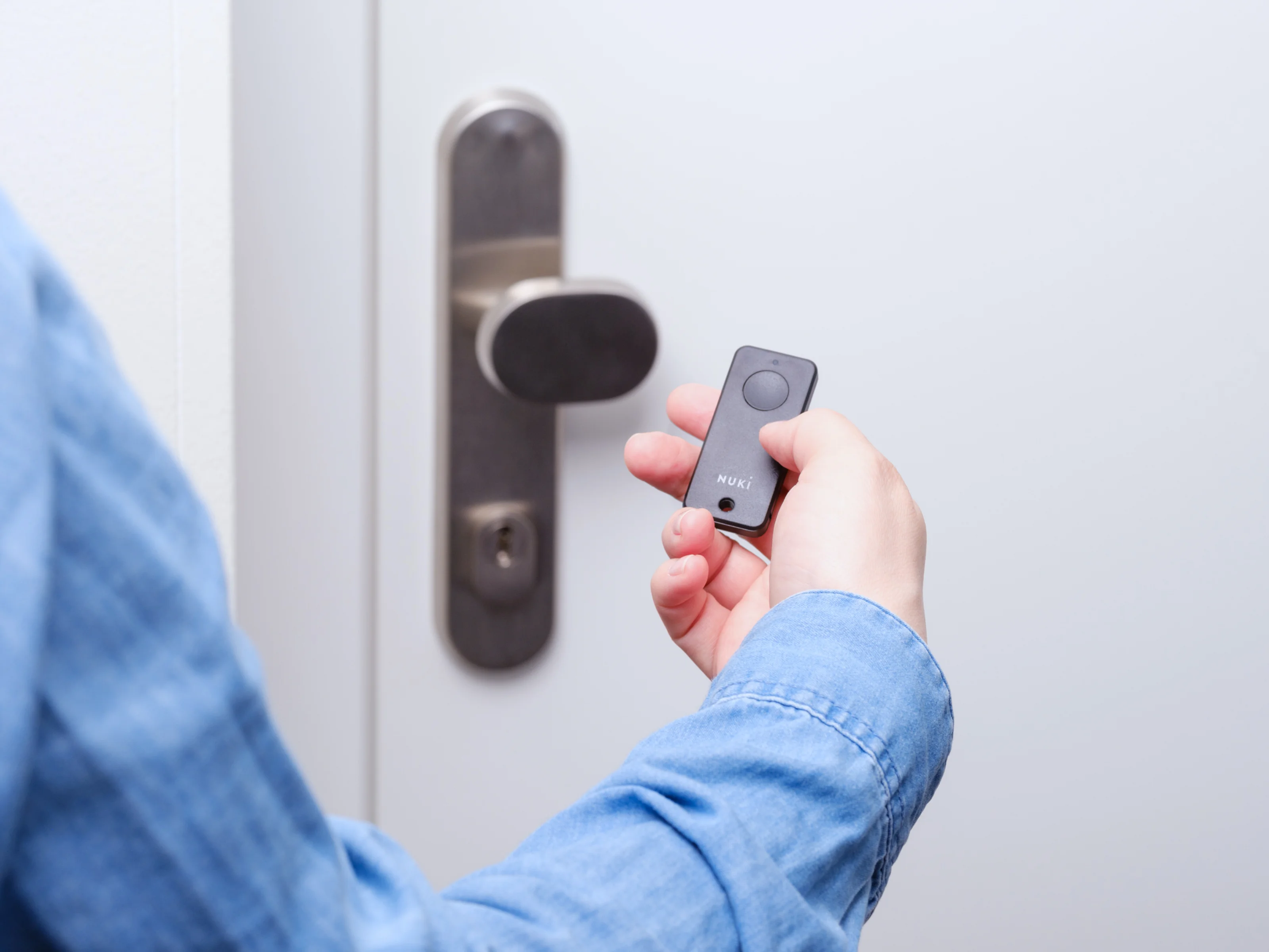 Persona apre una porta con il Nuki Fob e il Nuki Smart Lock.