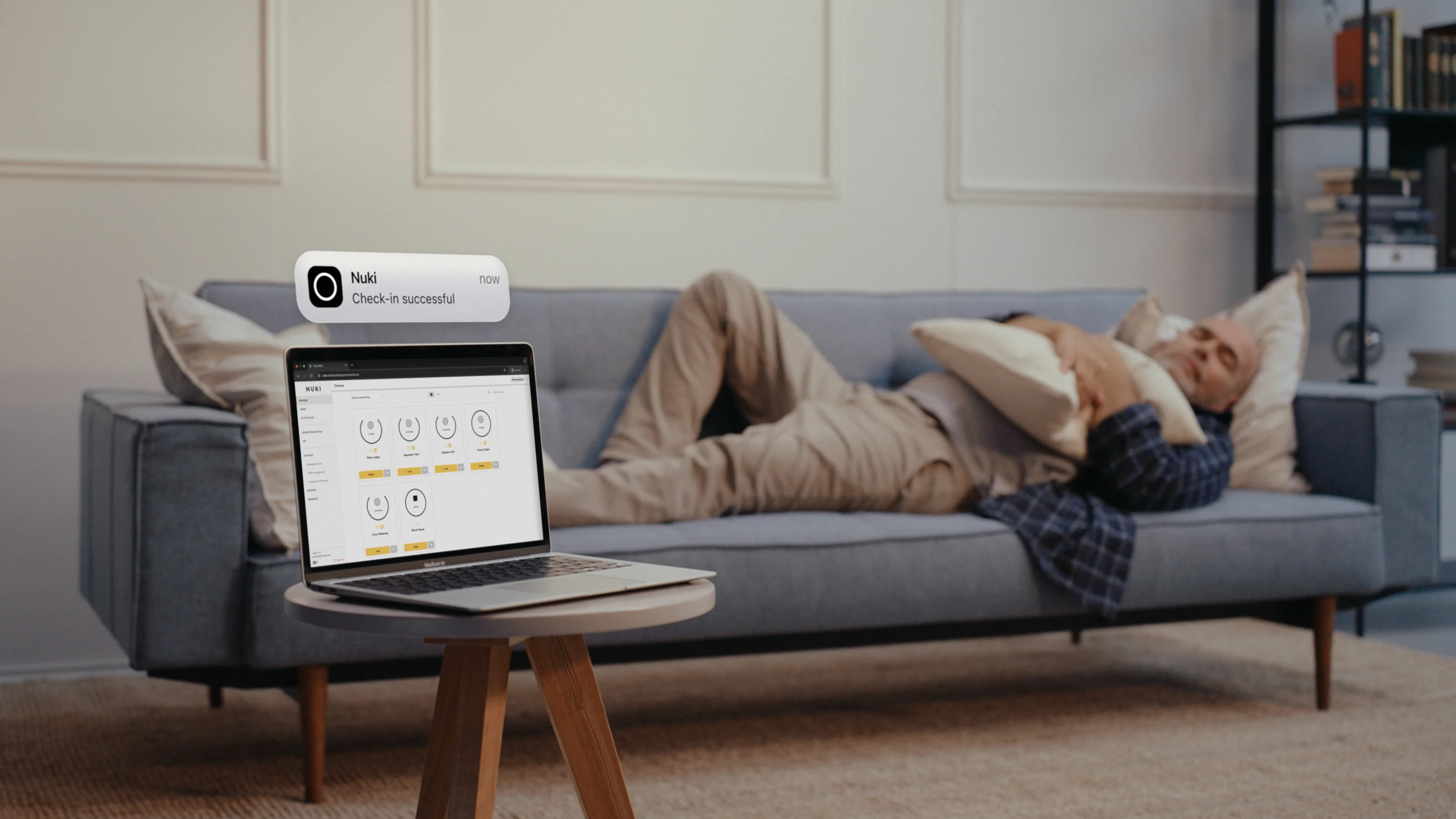 Uomo rilassato controlla l’accesso tramite l’app Nuki dal suo laptop – gestione smart ovunque.