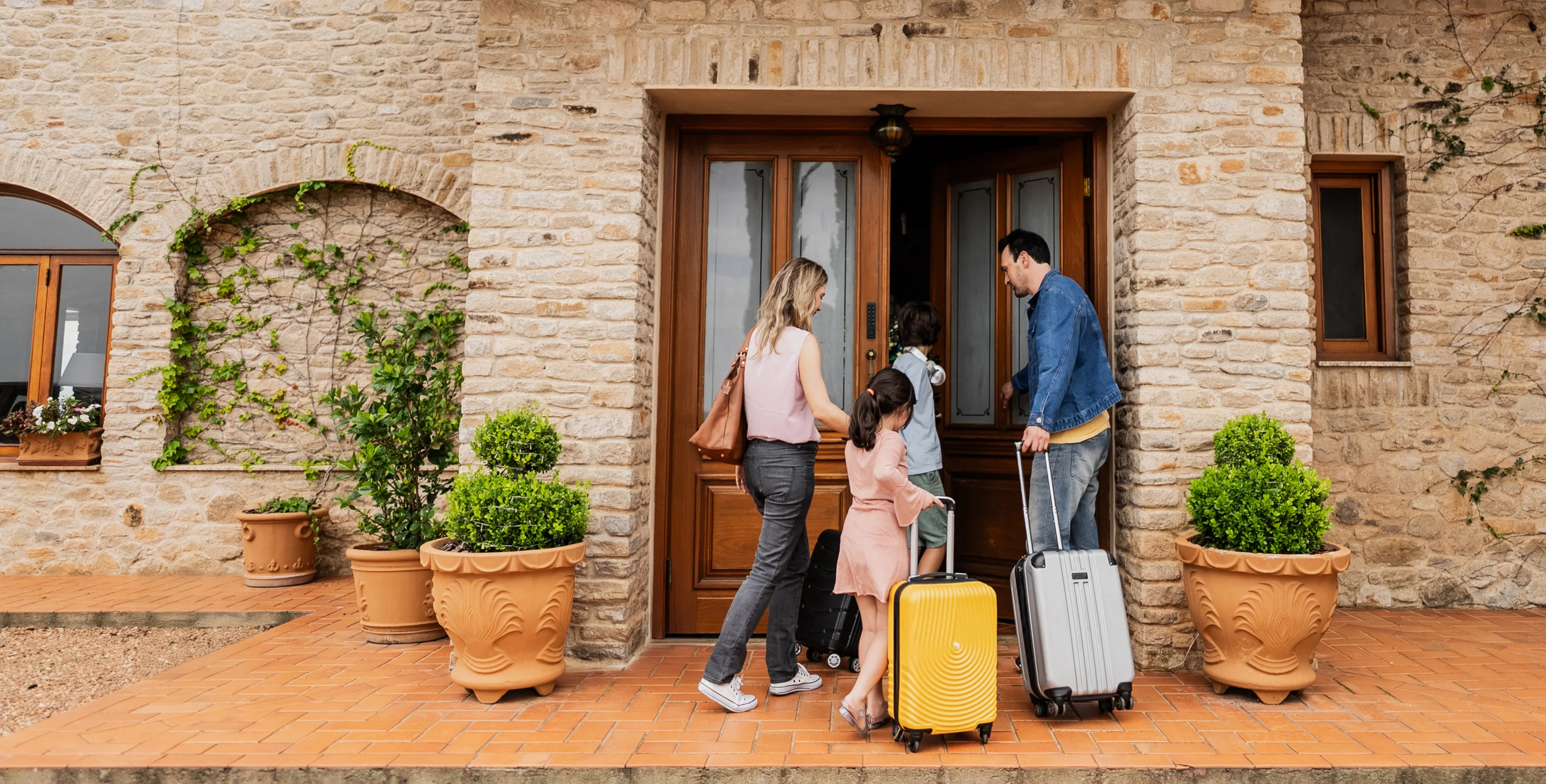 Eine Familie mit Koffern öffnet die Tür eines Ferienhauses mit einem Nuki Keypad.