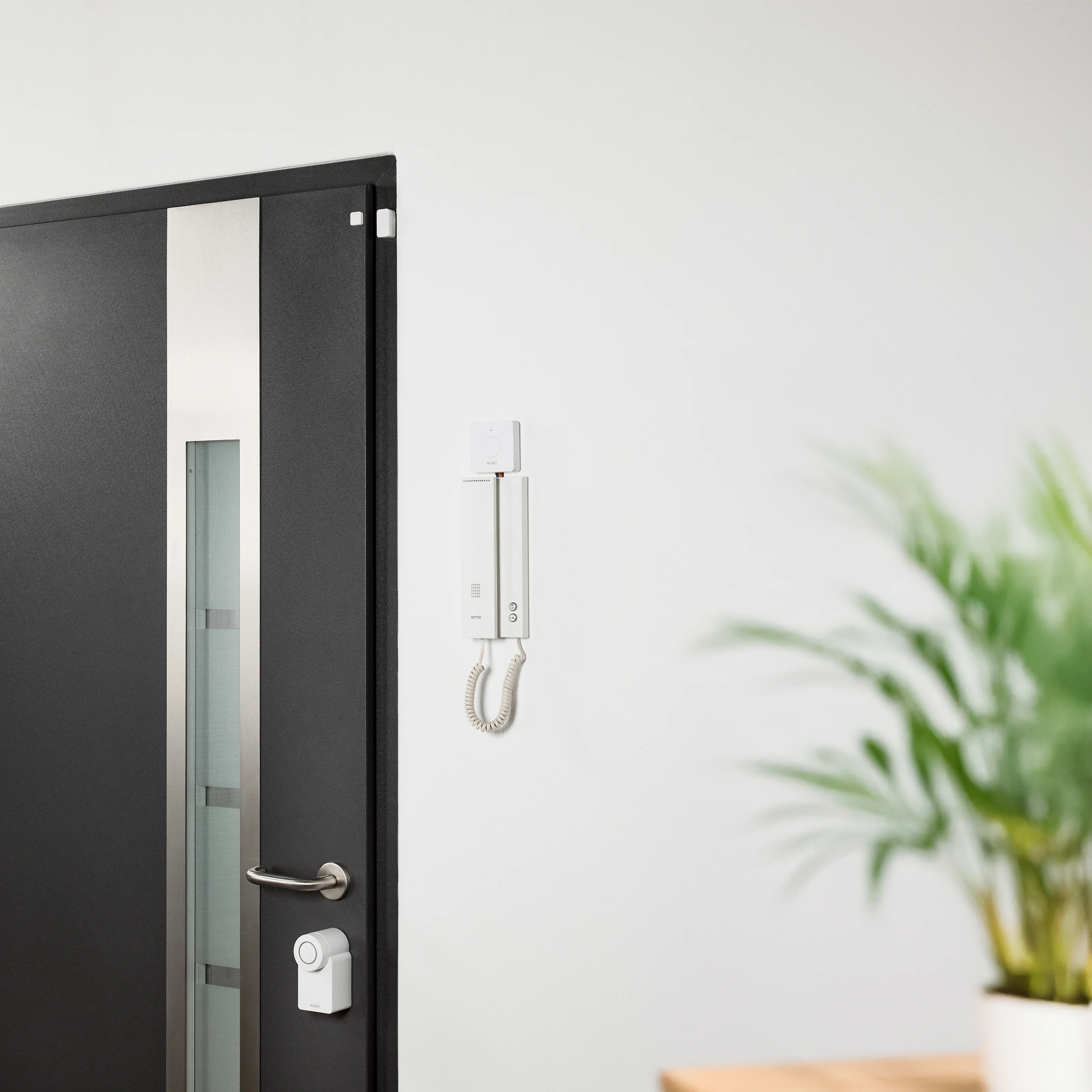 Nuki Smart Lock, Door Sensor e Opener installati su porta d’ingresso e citofono moderni.