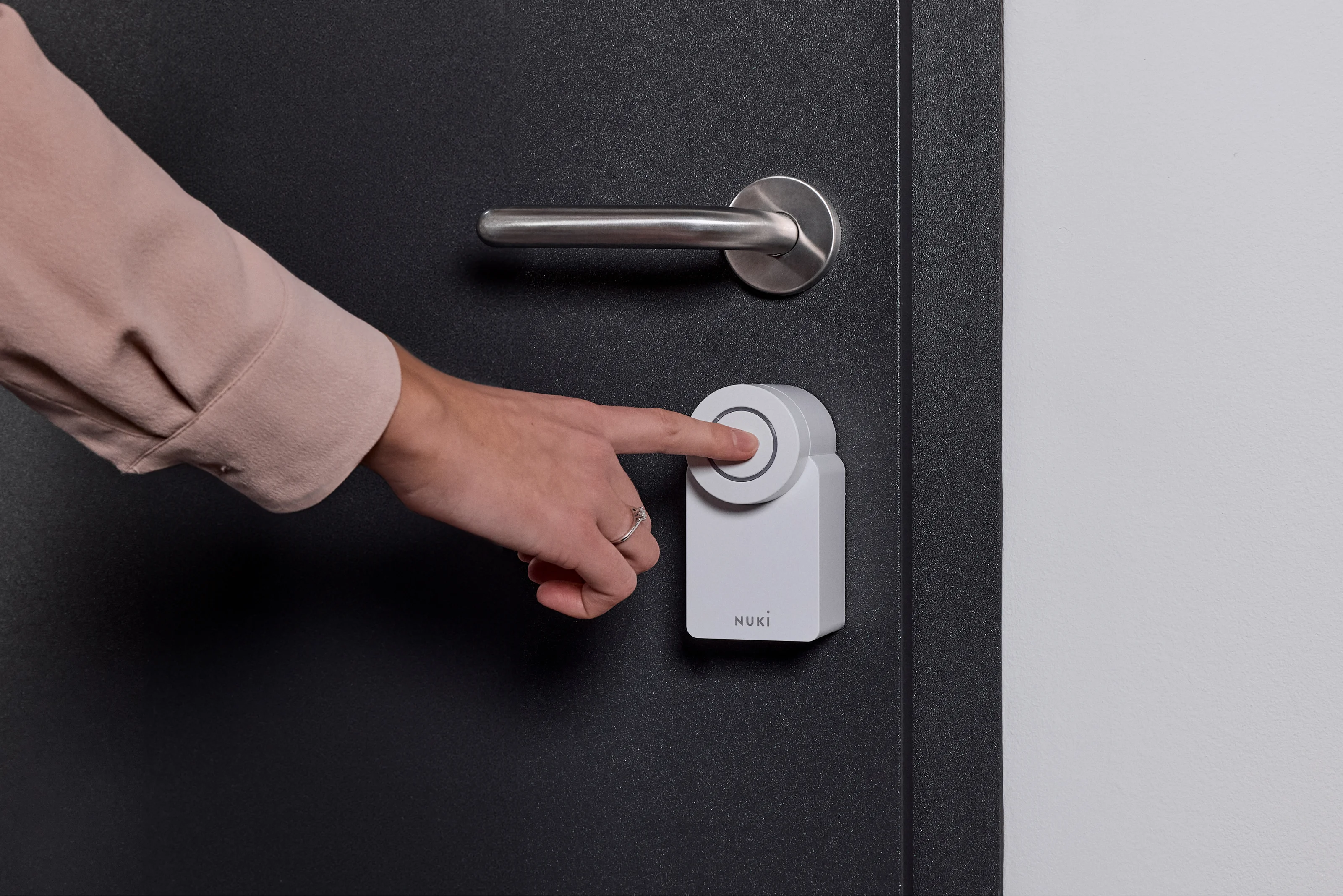 Utente apre la porta premendo il Nuki Smart Lock Go – accesso smart senza chiavi.