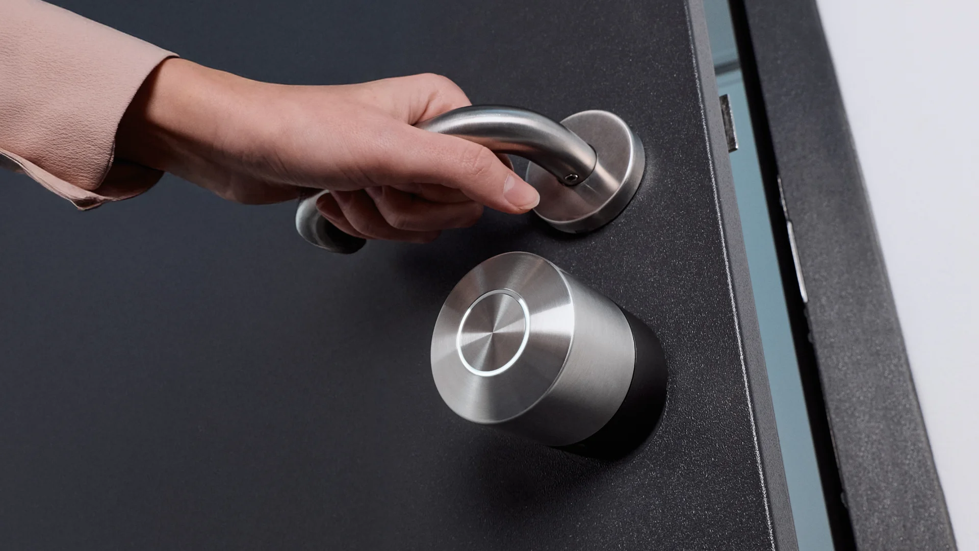 Mano sulla maniglia accanto al Nuki Smart Lock Pro – accesso smart semplificato.