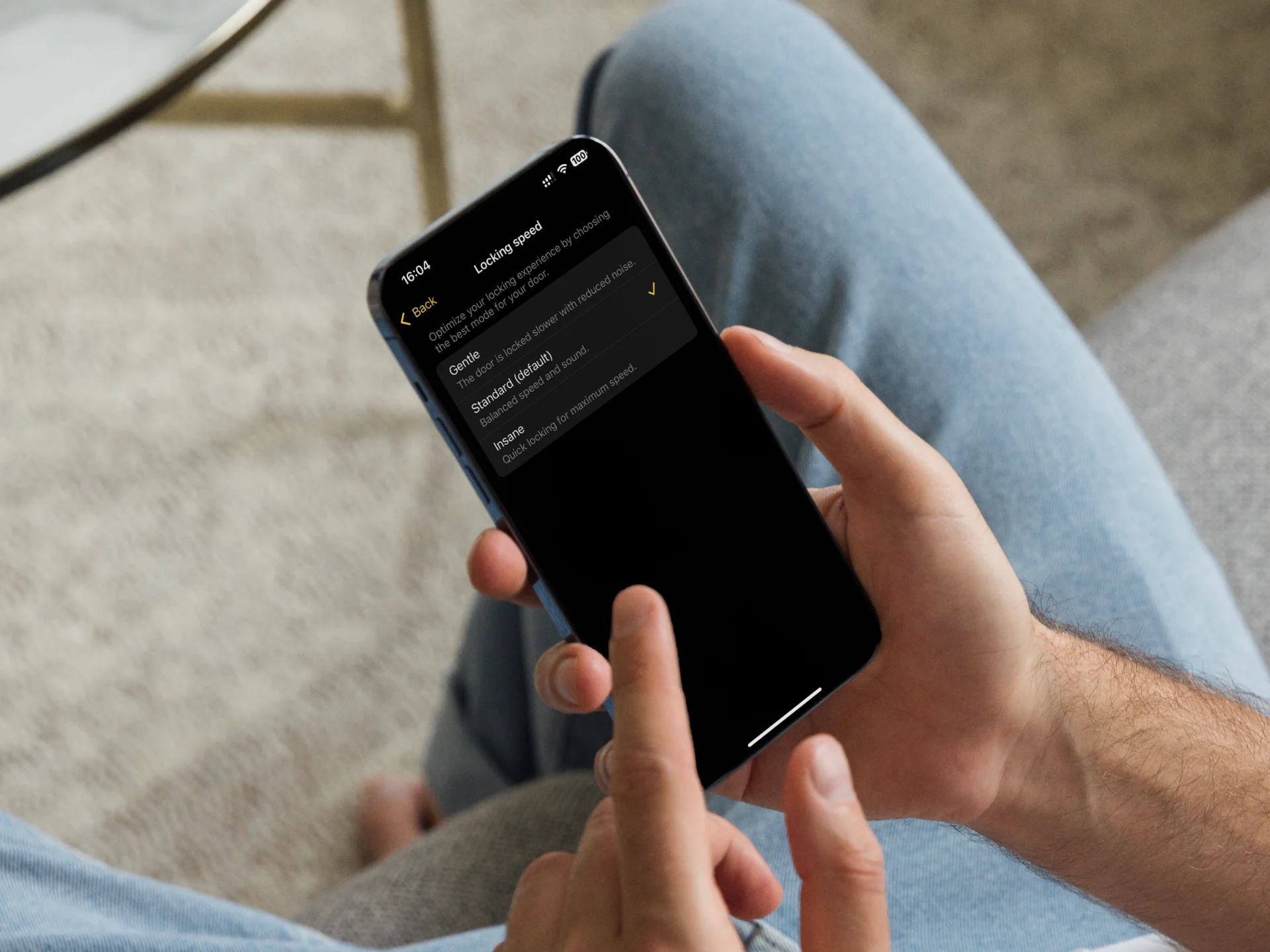 Utente gestisce le impostazioni della serratura tramite l’app Nuki – controllo sicuro dal divano.