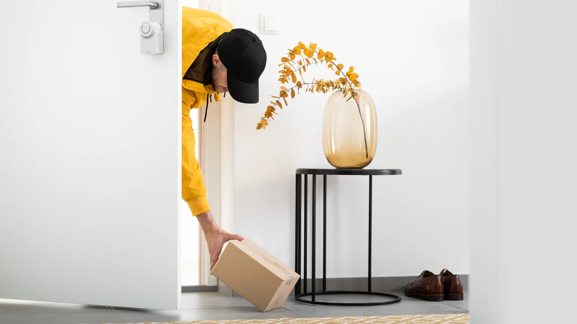 Corriere lascia un pacco attraverso la porta aperta con la Nuki Smart Lock.