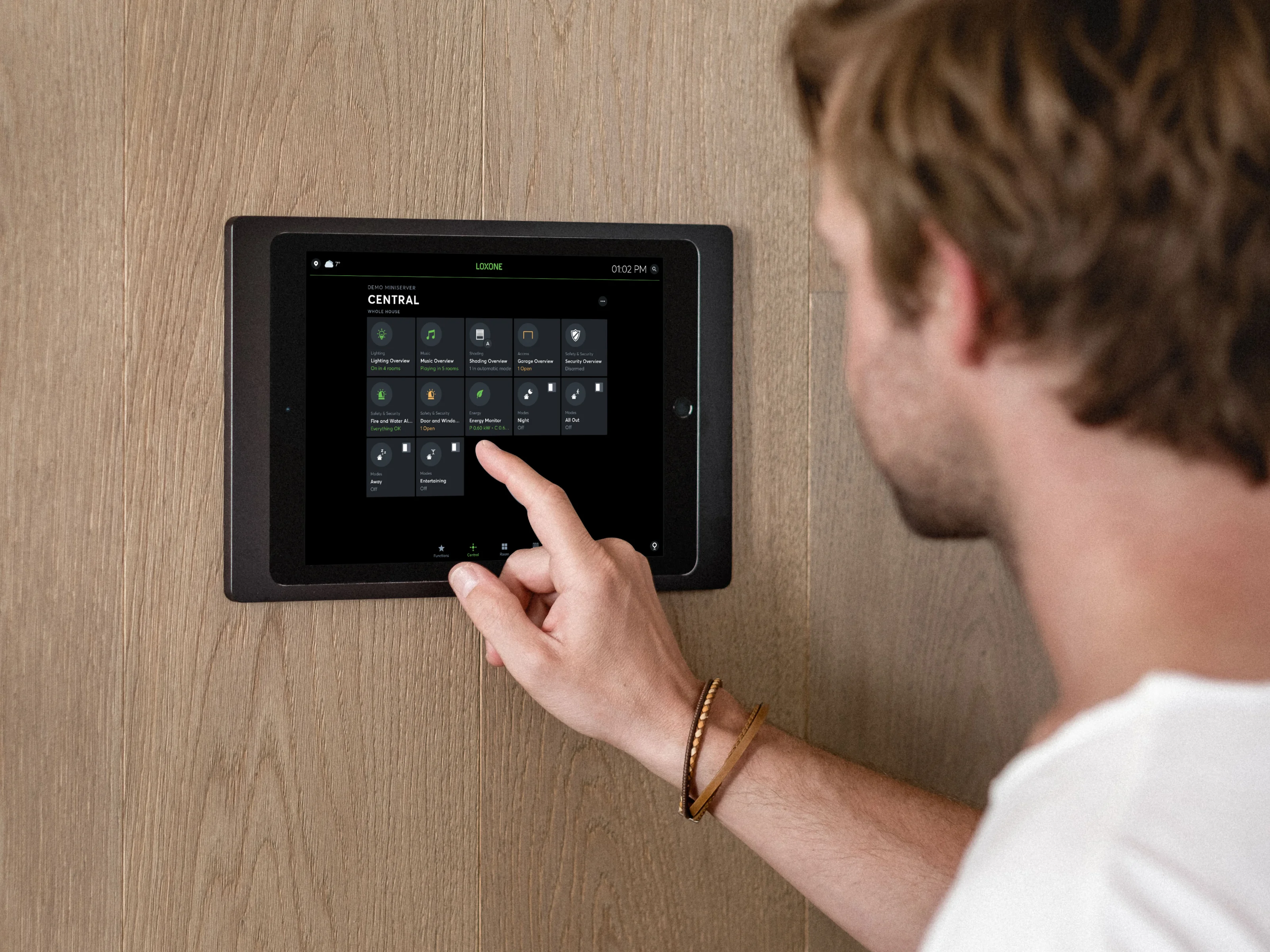 Homme pilotant des fonctions domotiques via une tablette murale avec l’app Loxone.