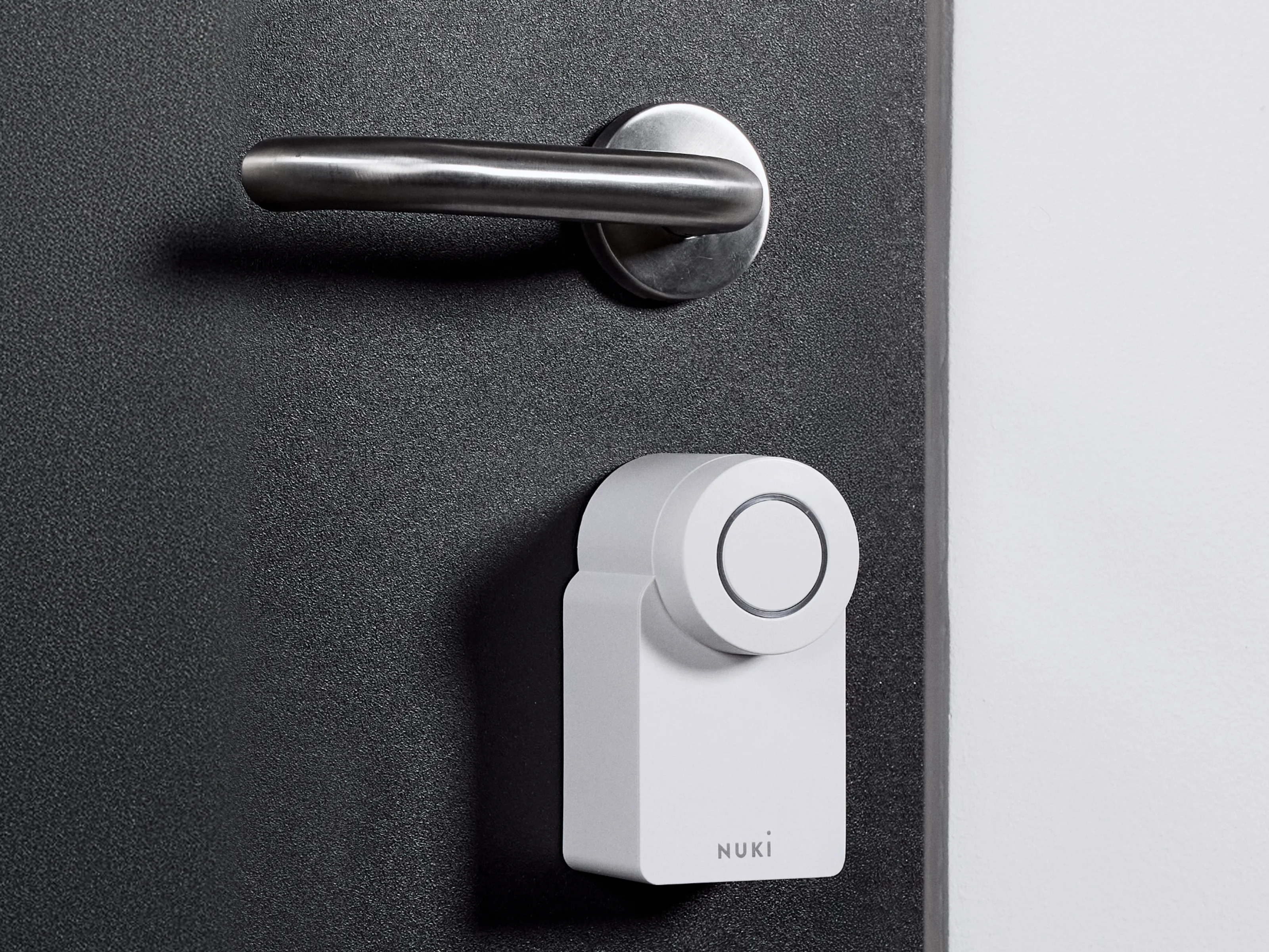 La Nuki Smart Lock Go montata su una porta scura con ferramenta argento.