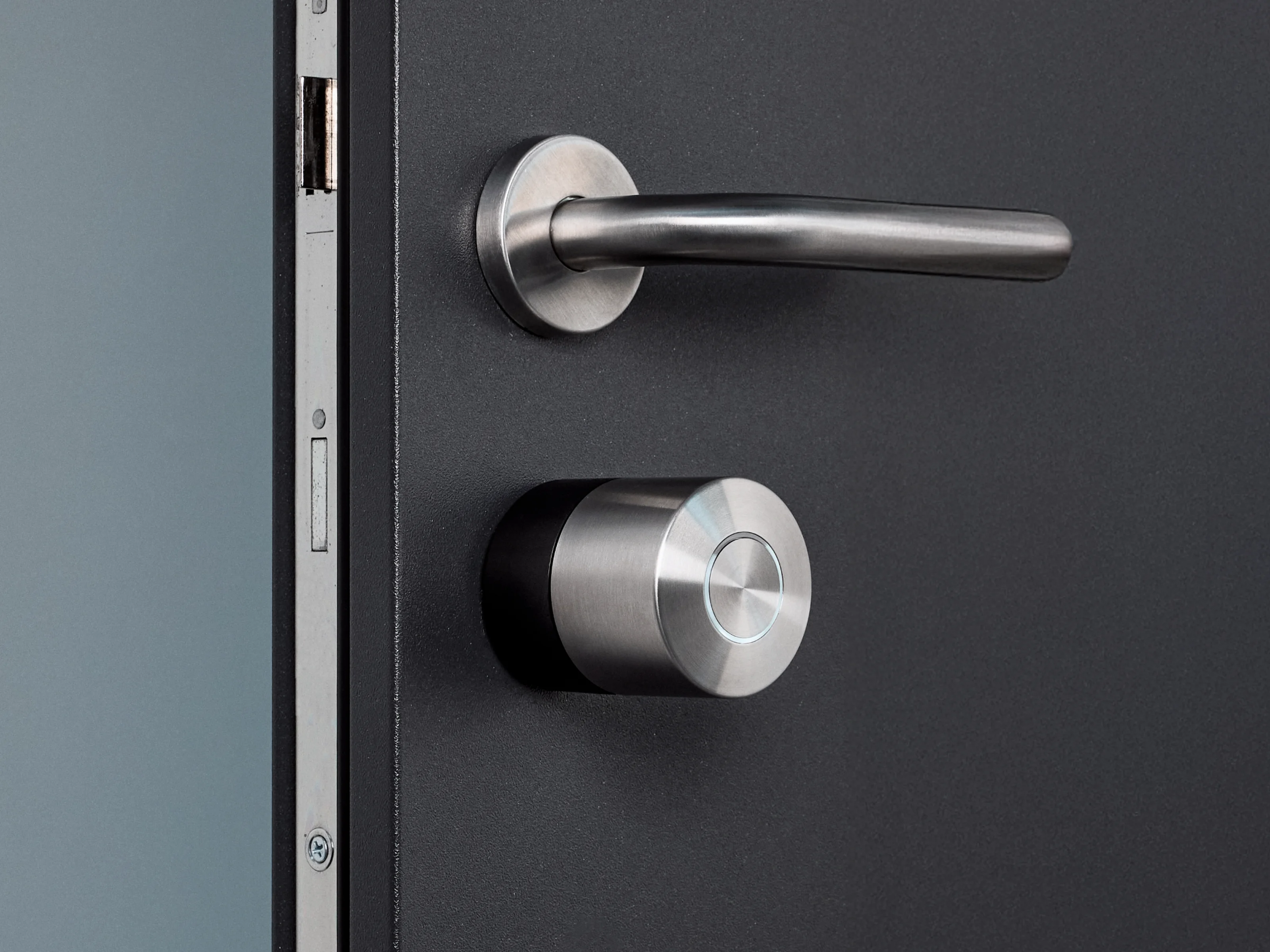 La Nuki Smart Lock Pro con anello nero montata su una porta scura con ferramenta argento.
