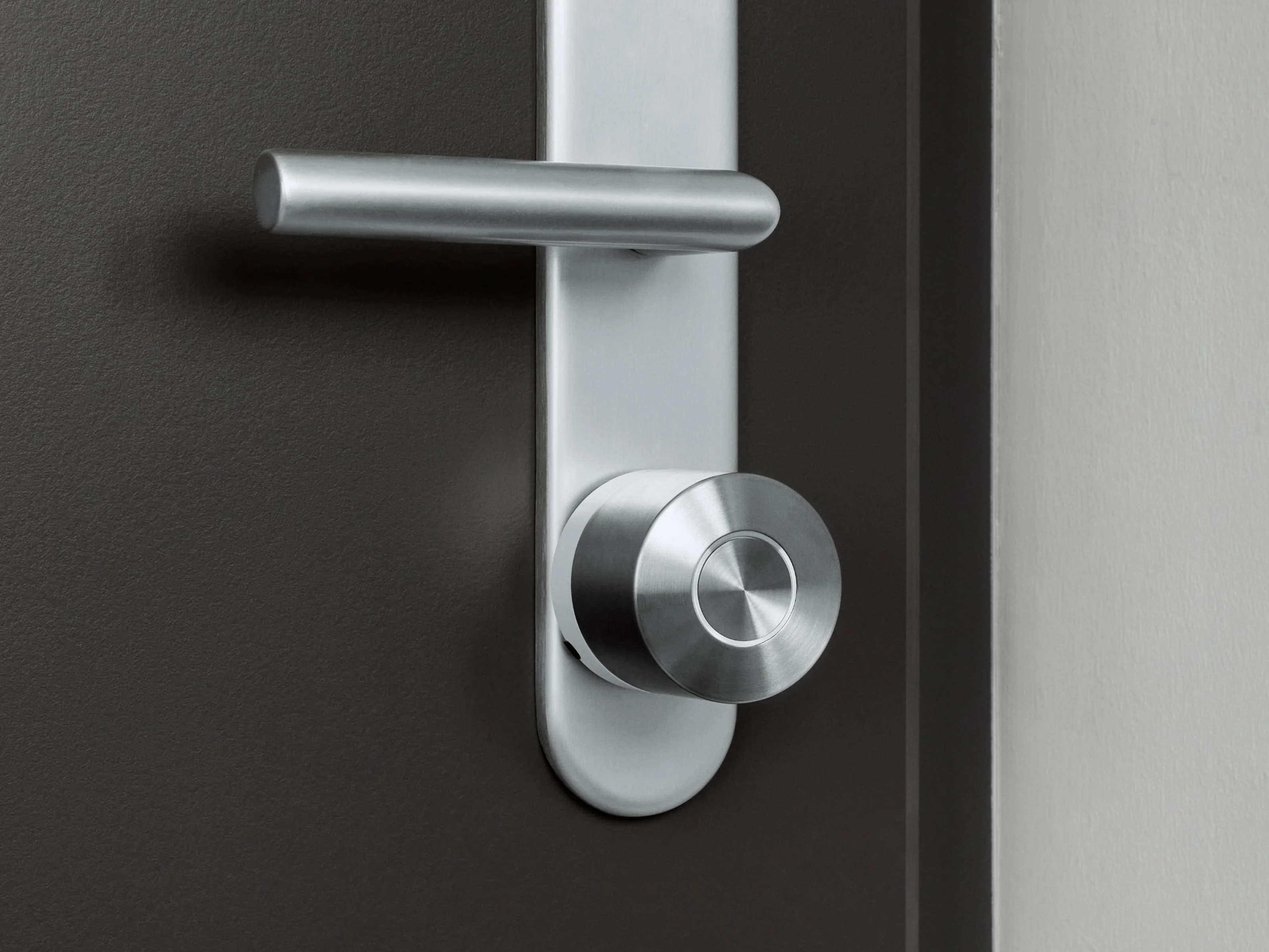 La Nuki Smart Lock Ultra con anello bianco montata su una porta scura con ferramenta argento.