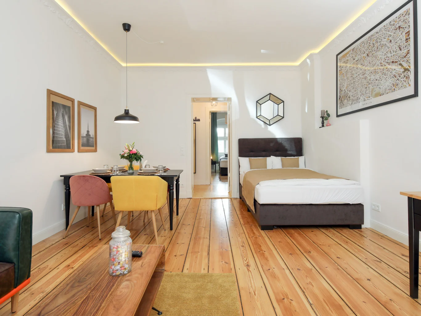 Stanza accogliente con letto, tavolo da pranzo e divano, in legno e bianco.