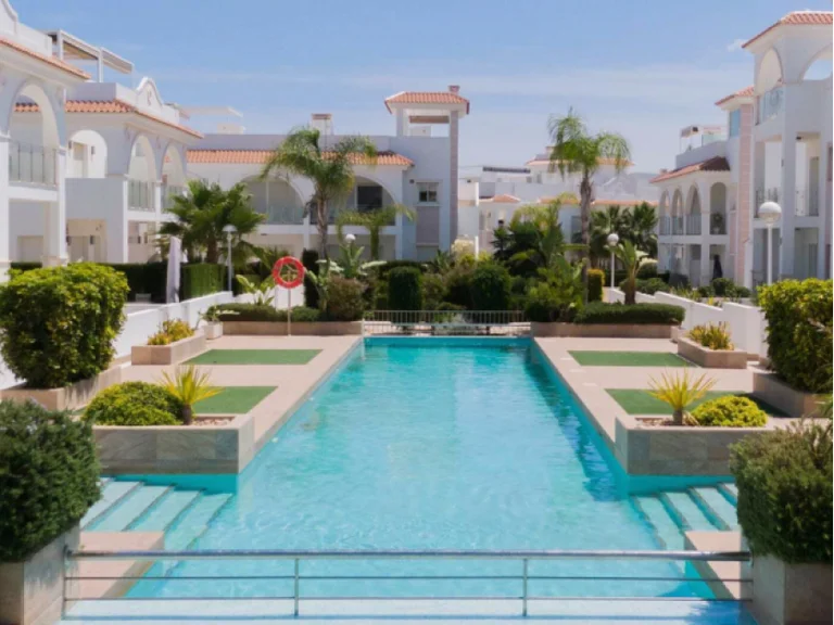 Interno di un complesso bianco con piscina e aree verdi.