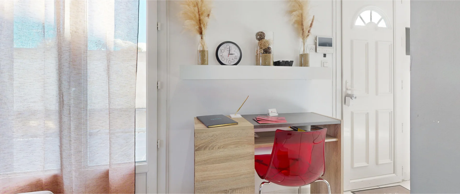 Interno di un appartamento con ampia finestra, scrivania e design moderno e neutro.