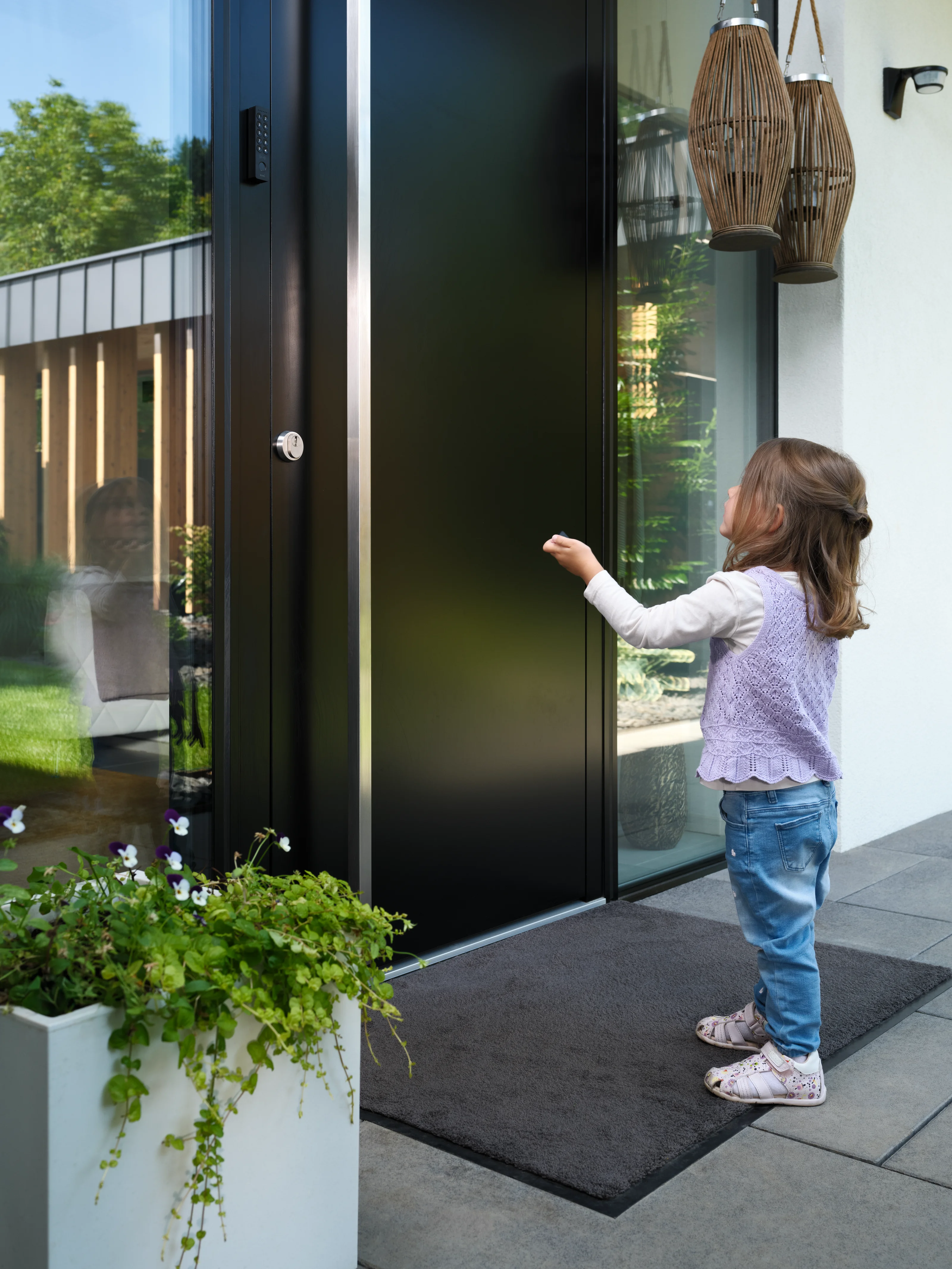 Bambina in piedi davanti alla porta d’ingresso che punta un portachiavi verso la porta.