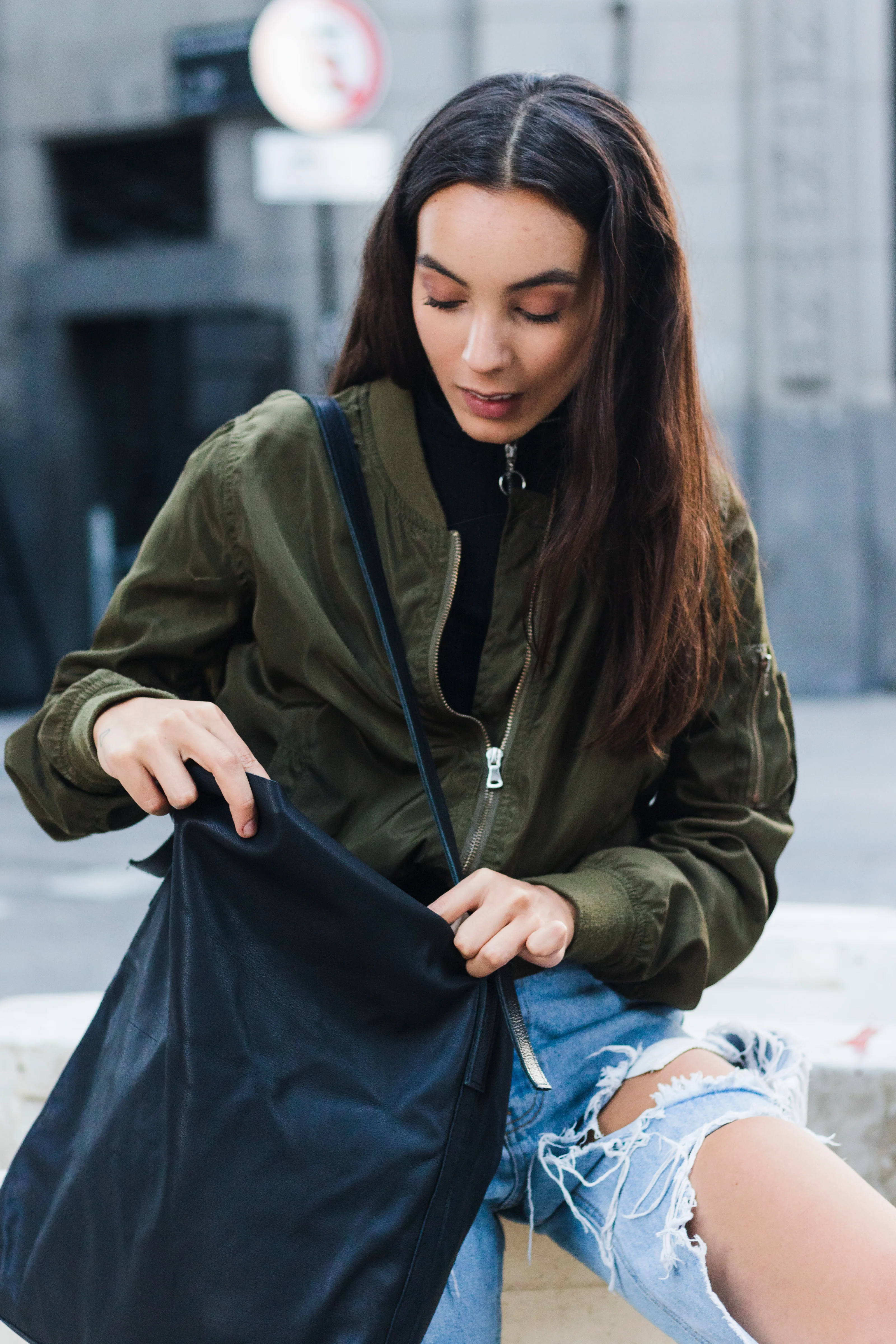 Giovane donna in città che cerca nella sua borsa.