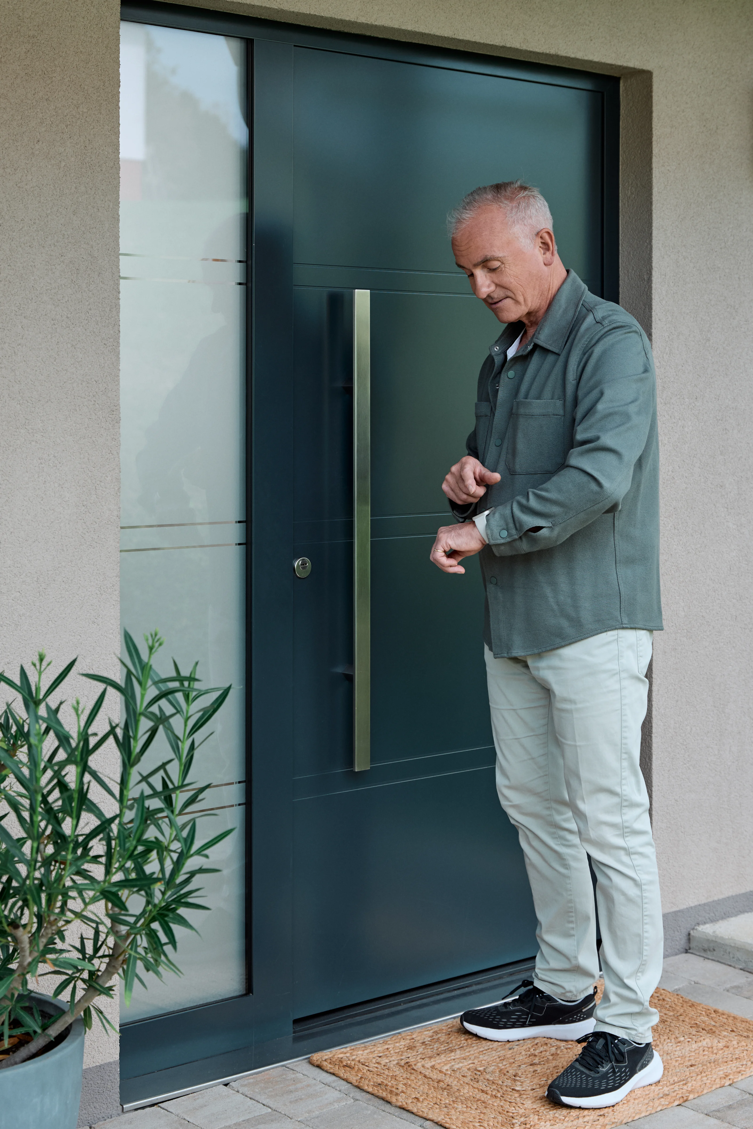 Uomo davanti alla porta di casa che guarda il suo smartwatch.